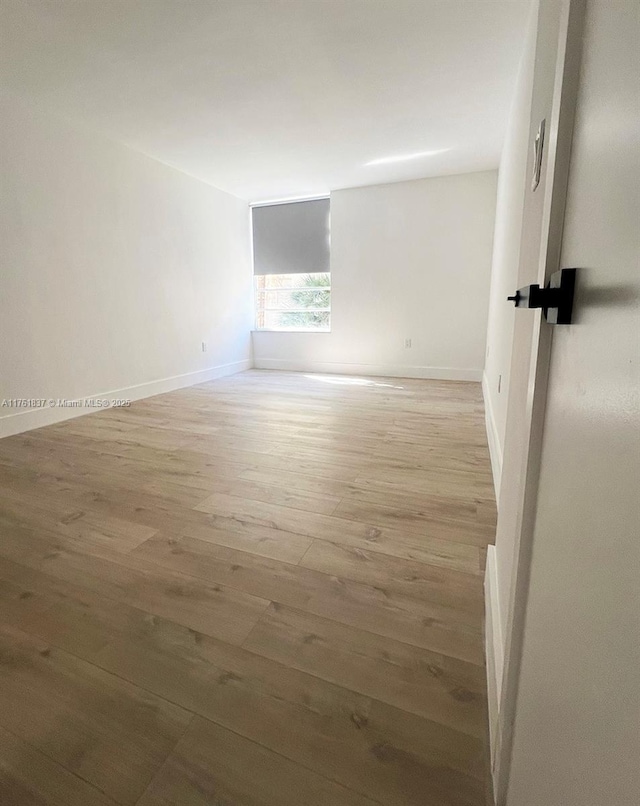 unfurnished room featuring baseboards and light wood finished floors