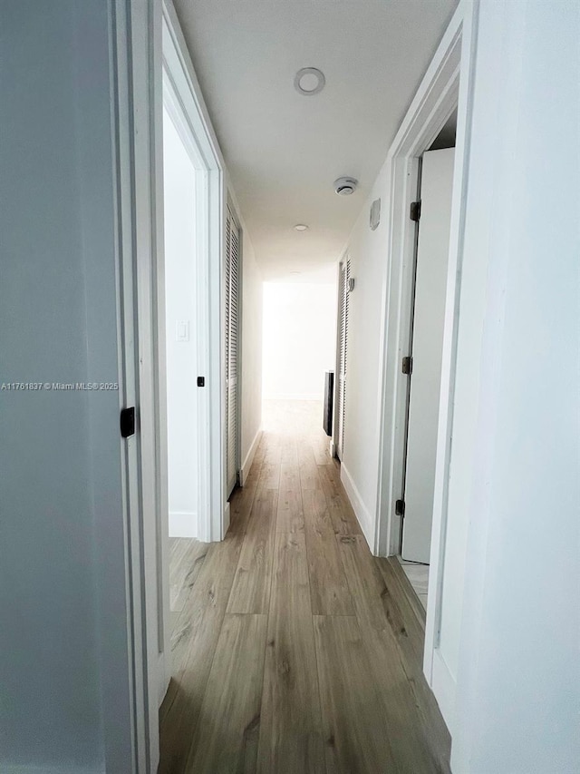 corridor with wood finished floors and baseboards