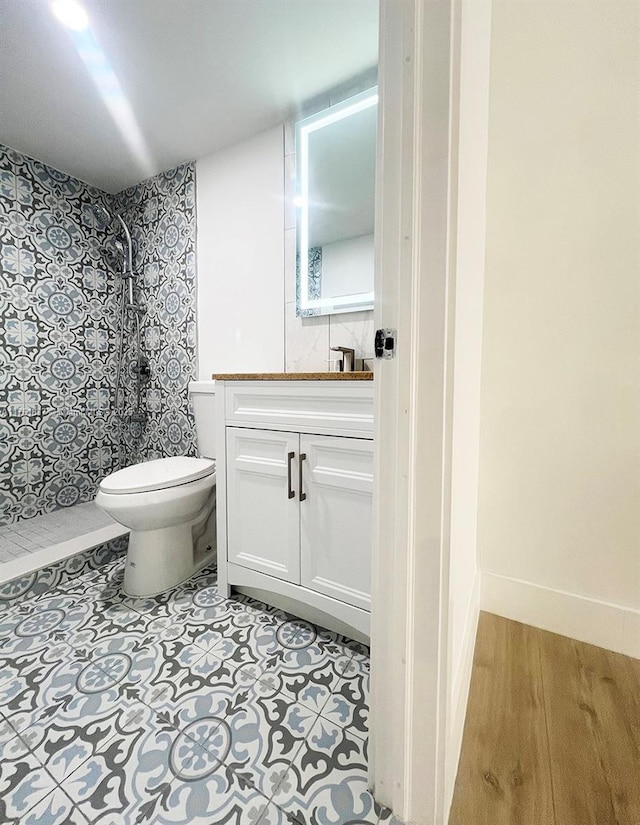 bathroom featuring vanity, toilet, baseboards, and walk in shower