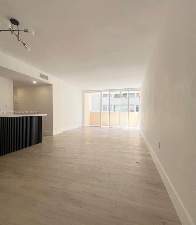 empty room featuring visible vents, baseboards, light wood-style floors, and floor to ceiling windows