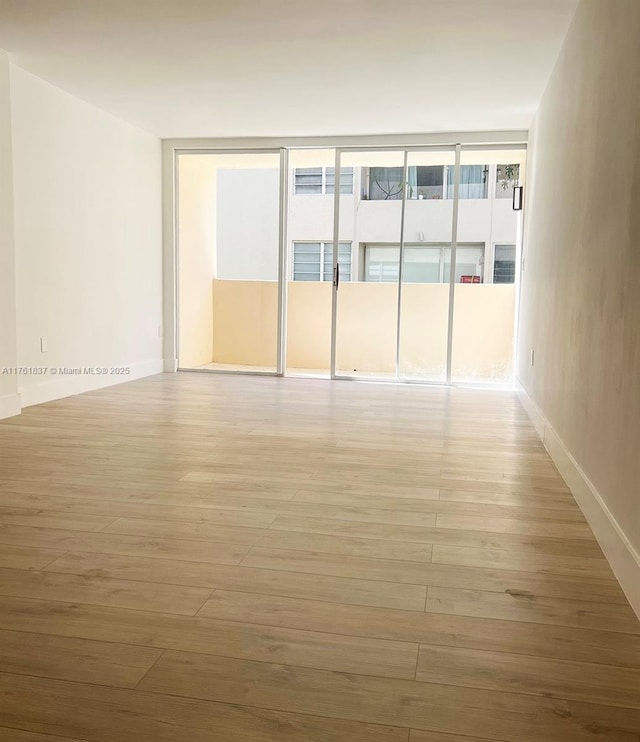 spare room featuring baseboards and light wood-style flooring