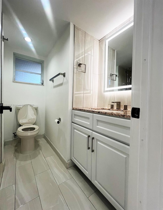 bathroom with baseboards, toilet, and vanity