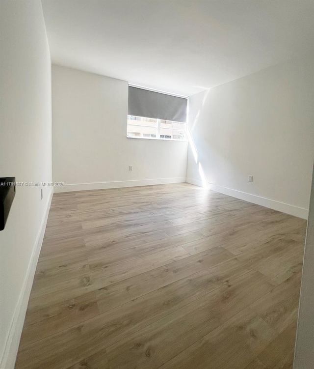 spare room featuring lofted ceiling, wood finished floors, and baseboards