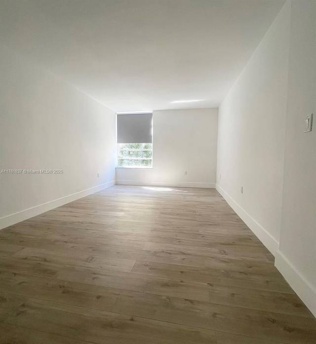 unfurnished room with baseboards and wood finished floors