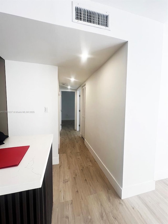 corridor featuring light wood-style flooring, baseboards, and visible vents