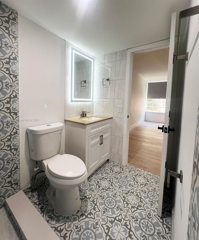 bathroom featuring tile patterned flooring, toilet, vanity, and tile walls