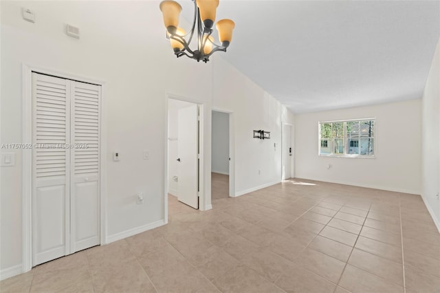 interior space featuring light tile patterned floors, baseboards, lofted ceiling, and a chandelier