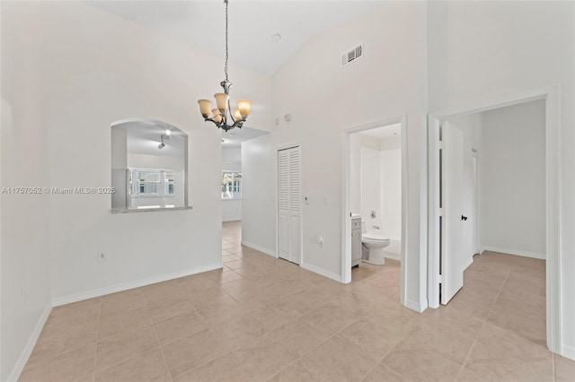 spare room with visible vents, baseboards, light tile patterned floors, arched walkways, and high vaulted ceiling