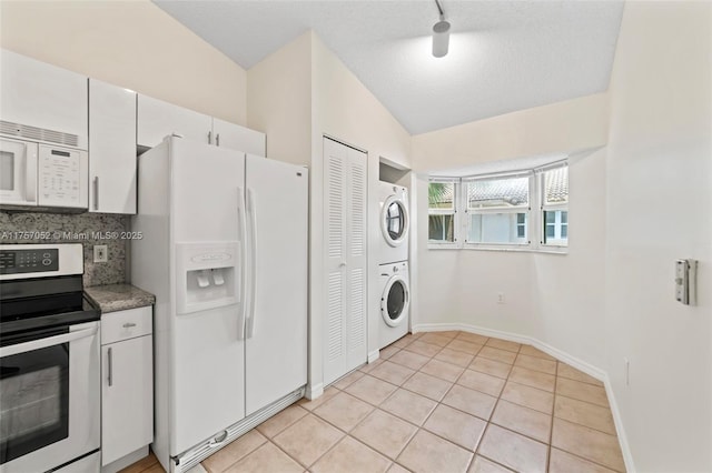 kitchen featuring light tile patterned floors, decorative backsplash, white appliances, and stacked washer and dryer