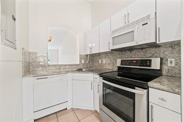 kitchen with a sink, backsplash, white appliances, white cabinets, and light tile patterned floors