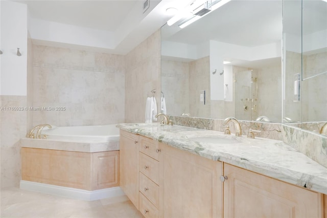 bathroom with tile walls, a bath, double vanity, and a sink