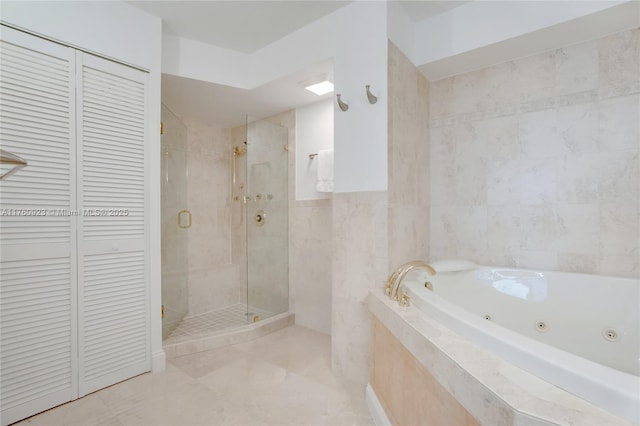 full bathroom featuring a jetted tub, a closet, tile walls, a shower stall, and tile patterned flooring