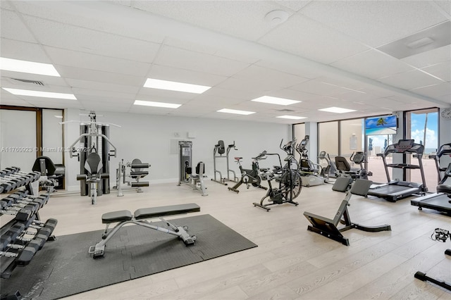 gym with wood finished floors, visible vents, a drop ceiling, and expansive windows