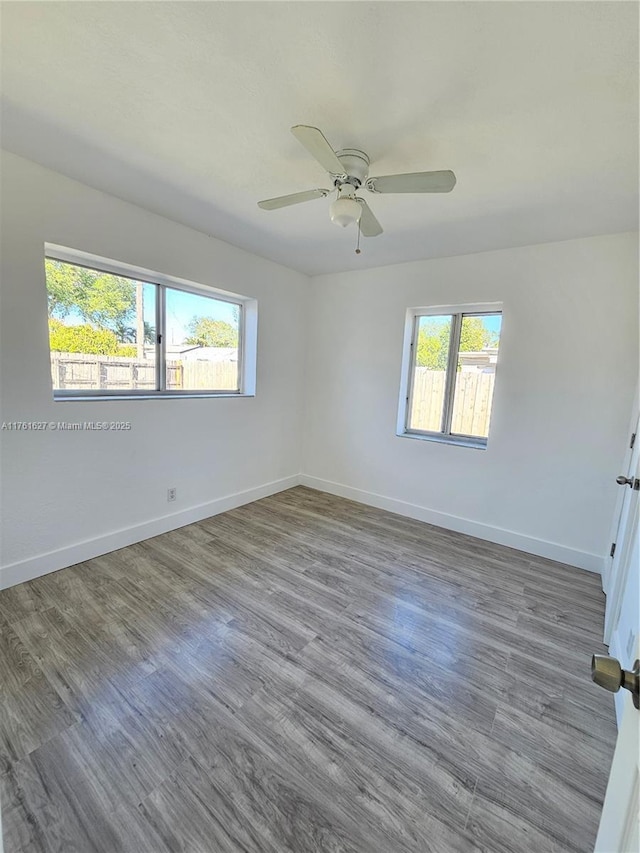 unfurnished room with a ceiling fan, baseboards, and wood finished floors