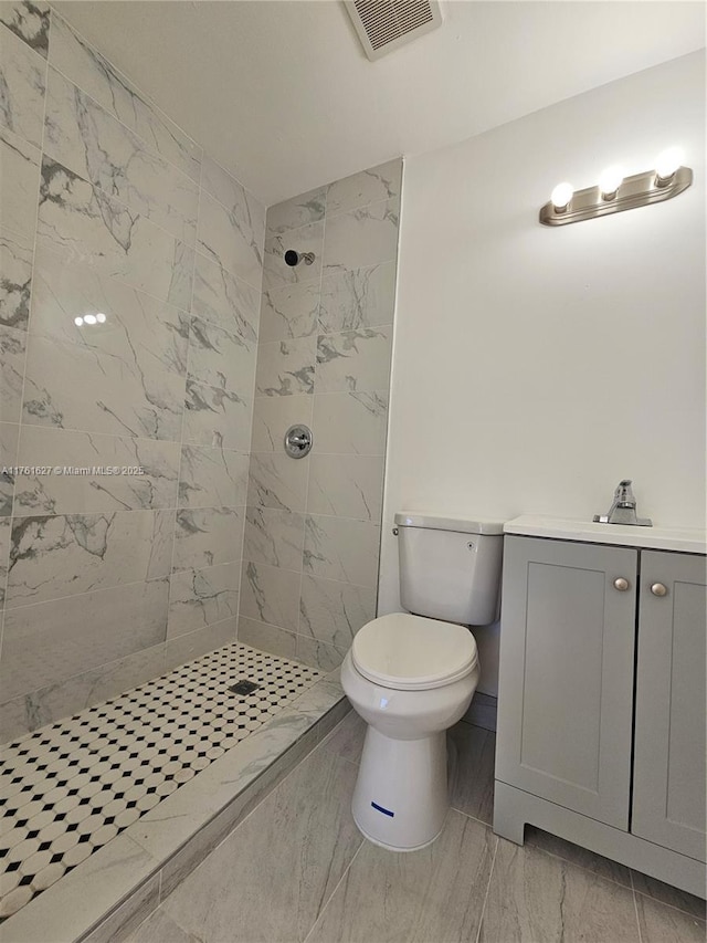 full bathroom with visible vents, toilet, marble finish floor, tiled shower, and vanity