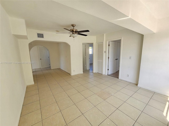 unfurnished room featuring arched walkways, visible vents, ceiling fan, and light tile patterned floors