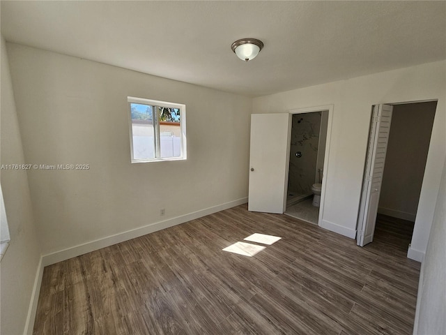 unfurnished bedroom featuring connected bathroom, baseboards, and wood finished floors