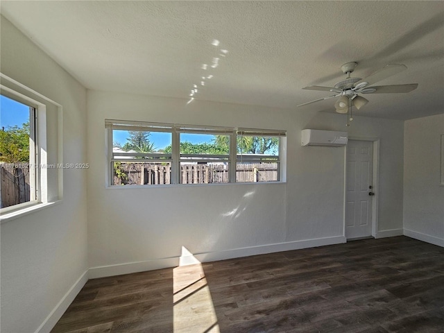 spare room with a healthy amount of sunlight, a wall mounted air conditioner, baseboards, and wood finished floors