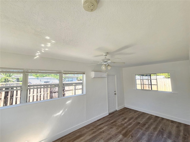 spare room with dark wood-style floors, baseboards, a wealth of natural light, and a wall unit AC