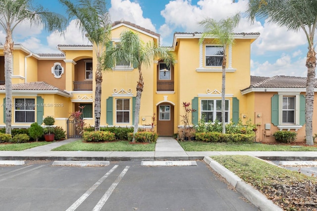 view of front of property featuring stucco siding, uncovered parking, and a tiled roof