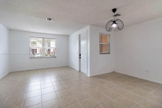 spare room featuring light tile patterned floors, visible vents, and a textured ceiling