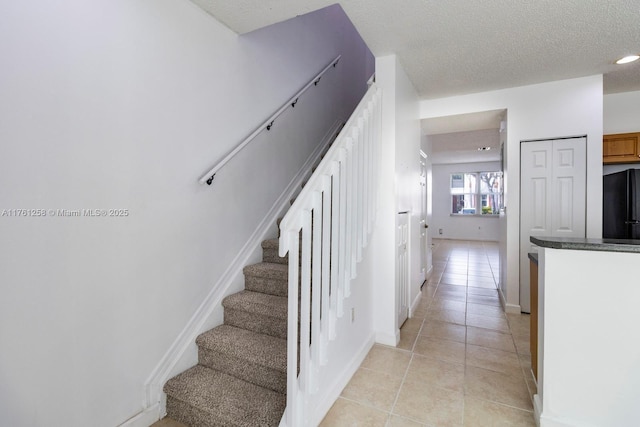 stairs with tile patterned floors, baseboards, and a textured ceiling