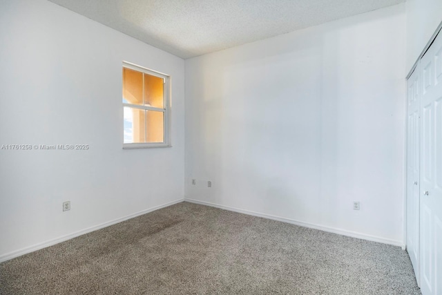 carpeted empty room with baseboards and a textured ceiling