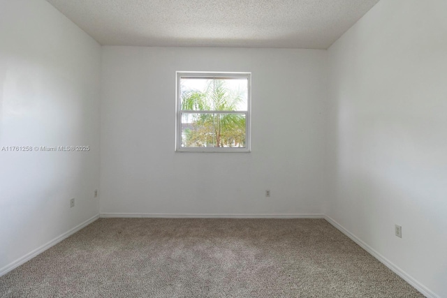 empty room with carpet, baseboards, and a textured ceiling