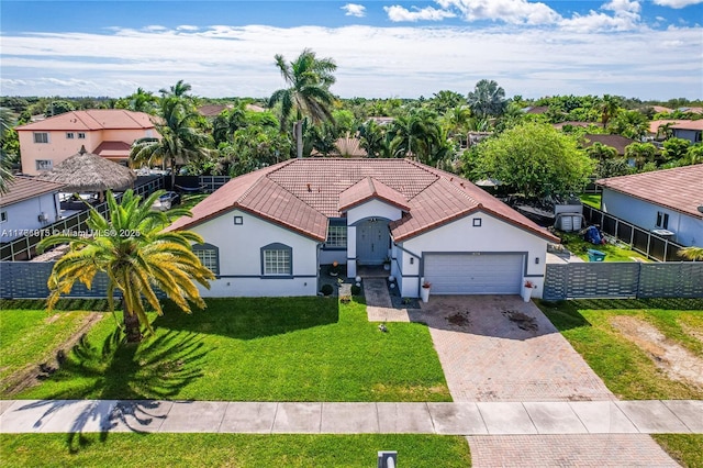 mediterranean / spanish-style house featuring stucco siding, decorative driveway, a front yard, and fence