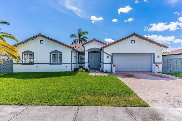 mediterranean / spanish home featuring stucco siding, decorative driveway, a front yard, and an attached garage