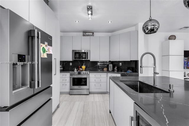 kitchen featuring visible vents, backsplash, dark stone countertops, stainless steel appliances, and a sink