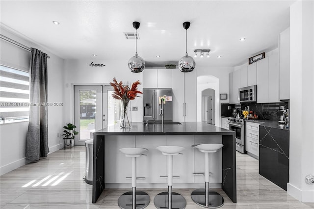 kitchen featuring dark countertops, visible vents, appliances with stainless steel finishes, arched walkways, and modern cabinets