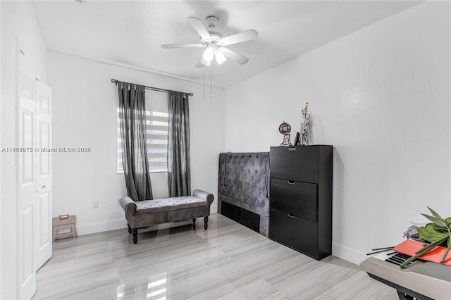 sitting room featuring a ceiling fan and baseboards