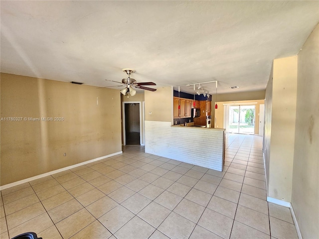 unfurnished living room featuring light tile patterned flooring, rail lighting, baseboards, and a ceiling fan