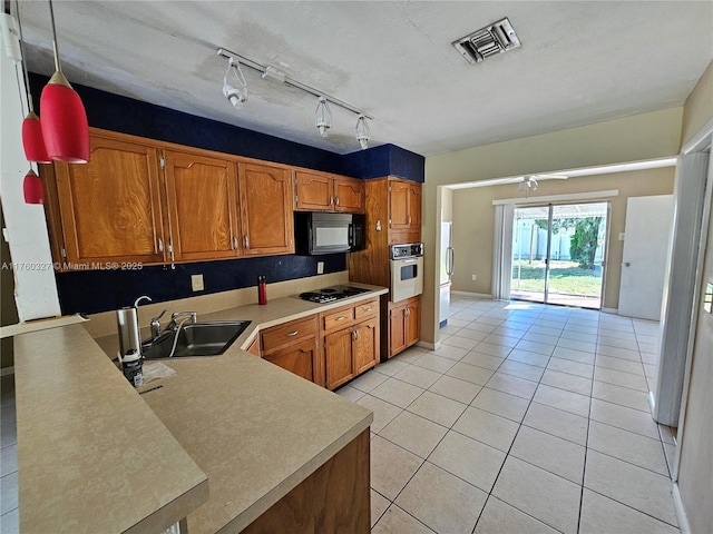 kitchen featuring brown cabinetry, visible vents, a sink, black appliances, and light countertops