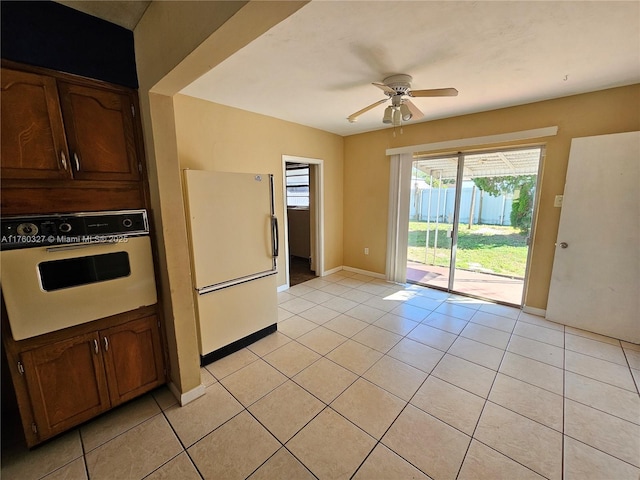 kitchen with white appliances, light tile patterned flooring, and baseboards