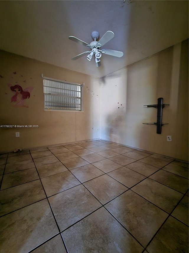 spare room with tile patterned floors and a ceiling fan