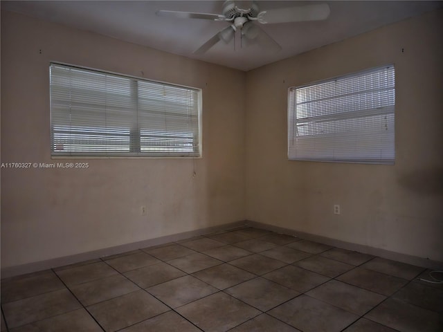 tiled empty room with baseboards, plenty of natural light, and ceiling fan