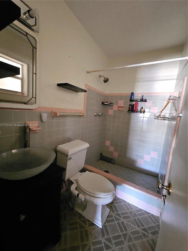 bathroom with vanity, tile walls, toilet, and a tile shower