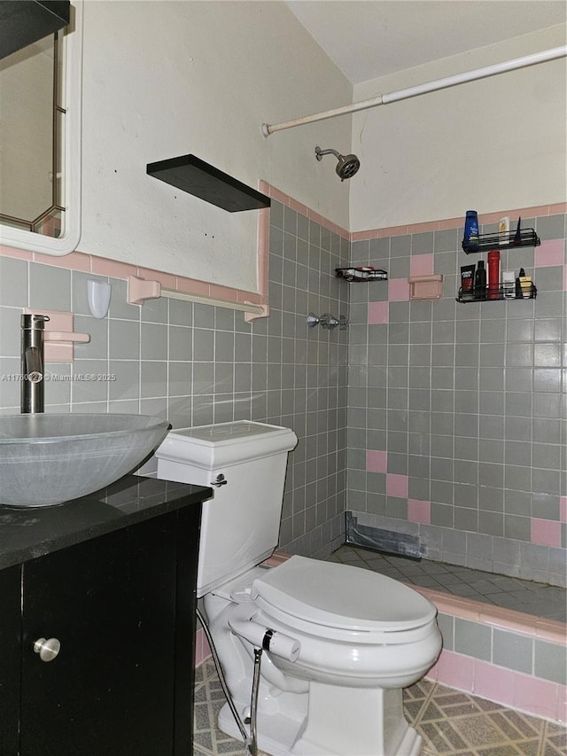 full bathroom with vanity, tile walls, toilet, and tiled shower