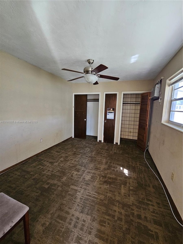 unfurnished bedroom with ceiling fan, baseboards, multiple closets, carpet flooring, and a wall mounted AC