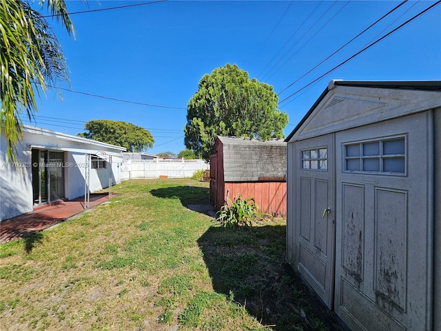 view of yard featuring an outbuilding, a storage unit, and fence