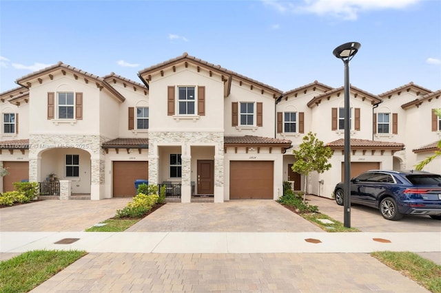 view of front facade featuring a garage, stone siding, driveway, and stucco siding