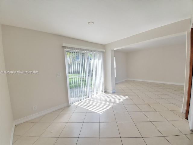 spare room featuring light tile patterned floors and baseboards