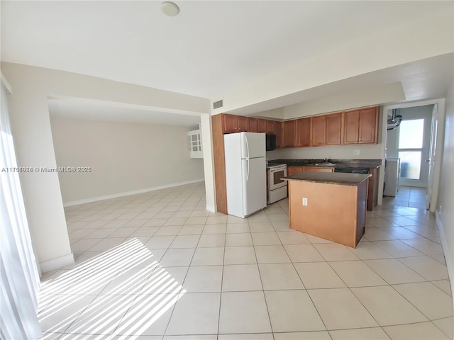 kitchen with dark countertops, visible vents, open floor plan, light tile patterned floors, and white appliances