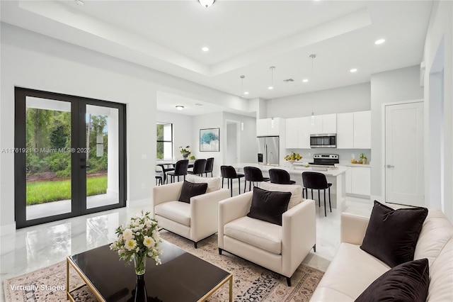 living area with a tray ceiling, french doors, and recessed lighting