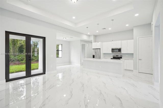 unfurnished living room with recessed lighting, french doors, and a tray ceiling