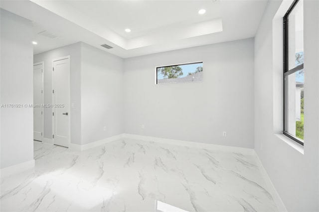 unfurnished room with a tray ceiling, plenty of natural light, recessed lighting, and visible vents