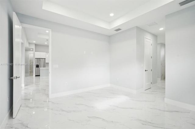 spare room featuring baseboards, visible vents, a tray ceiling, recessed lighting, and marble finish floor