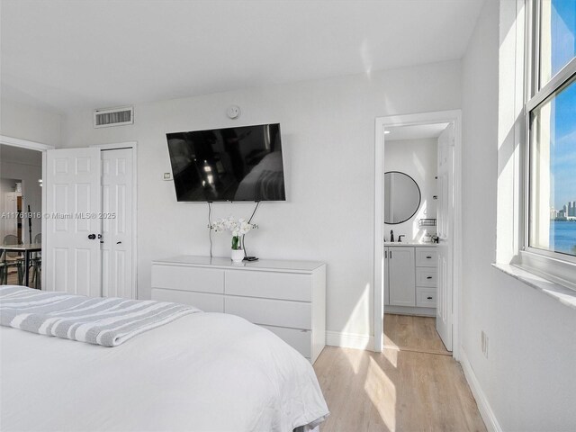 10350 W Bay Harbor Dr Unit 4H, Bay Harbor Islands, FL 33154 - bedroom with a sink, ensuite bathroom, baseboards, visible vents, and light wood-style floors